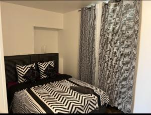a bedroom with a black and white bed and curtains at Lilas in Nogent-le-Rotrou