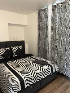 a bedroom with a black and white bed and curtains at Lilas in Nogent-le-Rotrou
