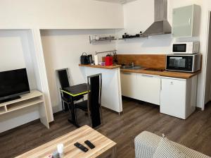 a small kitchen with white cabinets and a microwave at Lilas in Nogent-le-Rotrou