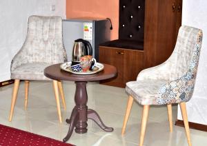 Duas cadeiras e uma mesa com uma chaleira de chá. em Hotel Shodlik em Samarkand