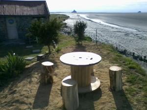 a table sitting on the beach next to a house at Cabane de douanier en baie du Mont Saint Michel hébergement insolite in Courtils