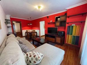 a living room with red walls and a couch at Erribera Etxea Amplio piso con parking in Bermeo