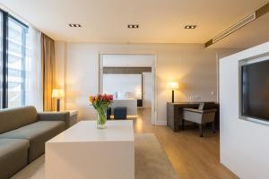 a living room with a couch and a table at Leonardo Royal Hotel Den Haag Promenade in The Hague