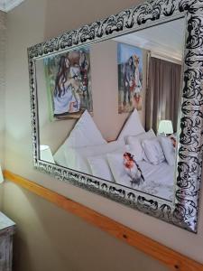 a mirror hanging on a wall above a bed at Rus en Rose Gastehuis in Bloemfontein