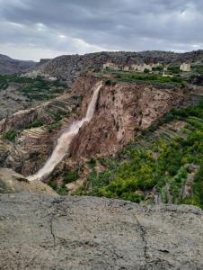 uma vista para um desfiladeiro com uma cascata numa montanha em نزل الريف التراثيه em Al ‘Aqar