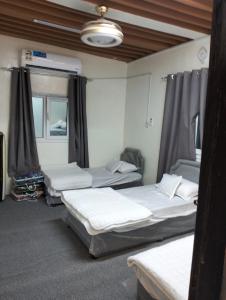 Zimmer mit 4 Betten und Vorhängen in der Unterkunft نزل الريف التراثيه in Al ‘Aqar