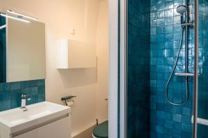 La salle de bains est pourvue d'un lavabo et d'une douche avec du carrelage bleu. dans l'établissement Charmant appartement 4 personnes en centre-ville, à Caen