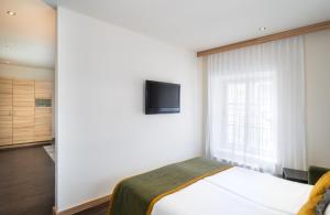 a bedroom with a bed and a tv on a wall at Leonardo Boutique Hotel Salzburg Gablerbräu in Salzburg