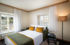 a hotel room with a bed and two windows at Leonardo Boutique Hotel Salzburg Gablerbräu in Salzburg