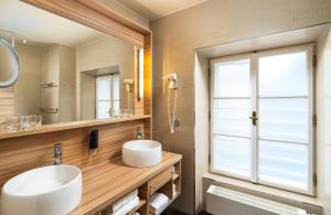 a bathroom with two sinks and a large mirror at Leonardo Boutique Hotel Salzburg Gablerbräu in Salzburg