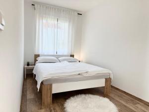 Cama en habitación blanca con ventana en Spacious Green Cosy Apartment near Maribor, en Pesnica pri Mariboru