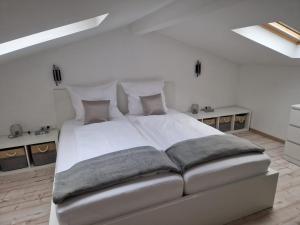 a white bedroom with a large white bed with pillows at Rhön Apartments in Frankenheim