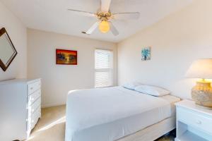 1 dormitorio con cama blanca y ventilador de techo en Flip Flop Inn, en Holden Beach