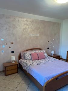 Schlafzimmer mit einem Bett mit blauer Bettwäsche und rosa Kissen in der Unterkunft La Corte Sul Lago casa vacanze in Pisogne