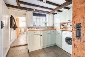 a kitchen with white cabinets and a washer and dryer at Sage Cottage in Ditchling