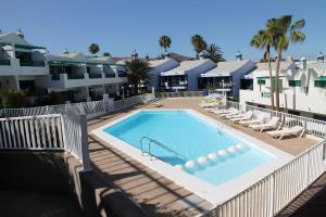 een zwembad met ligstoelen en een resort bij Bonito apartamento cerca la playa in San Bartolomé
