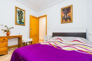 sypialnia z łóżkiem z fioletowym kocem w obiekcie ALEGRIA ID110 w mieście Torrevieja