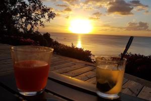 フンシャルにあるGranny House Madeiraの夕日を眺めながらテーブルの上でドリンク2杯