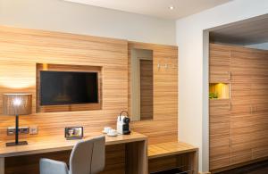 a room with a desk and a television on a wall at Leonardo Boutique Hotel Salzburg Gablerbräu in Salzburg