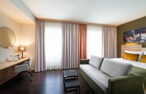 a hotel room with a bed and a couch and a desk at Leonardo Boutique Hotel Salzburg Gablerbräu in Salzburg