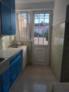 uma cozinha com armários azuis e uma porta com uma janela em THALIA'S GARDEN em Mytilini