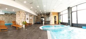 uma grande piscina numa sala com cadeiras e mesas em Filo Hotel Wellness & Spa em Gheorgheni