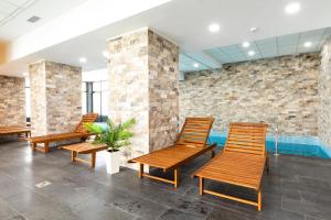 - une rangée de chaises en bois dans une chambre avec piscine dans l'établissement Filo Hotel Wellness & Spa, à Gheorgheni
