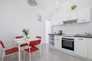 a white kitchen with red chairs and a table at Cozy Apartment Aleja Kijowska in Cracow by Renters in Krakow