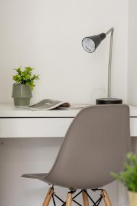 a white desk with a chair and a lamp at Cozy Apartment Aleja Kijowska in Cracow by Renters in Krakow