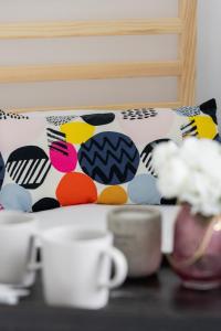 a bed with colorful pillows and cups on a table at Cozy Apartment Aleja Kijowska in Cracow by Renters in Krakow
