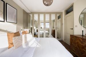 Schlafzimmer mit einem weißen Bett und einem Spiegel in der Unterkunft The Marylebone Escape - Lovely 1BDR Flat in London