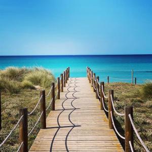 a wooden path leading to the ocean on a beach at Beach house in 1st sea line of Son Serra in Son Serra de Marina