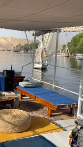 a boat with a table and a sailboat in the water at Freedom Houseboat in Aswan