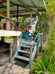 einer Bank und einer Treppe unter einer Holzkonstruktion in der Unterkunft Delima Cottage, Ngurbloat Beach in Ngurblut