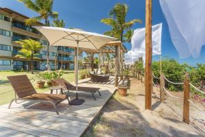 a patio with chairs and an umbrella in front of a hotel at Praia Muro Alto paradisíaco, Flat de 2 quartos. in Porto De Galinhas