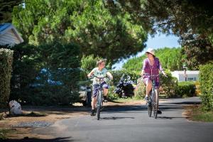 Chłopiec i dziewczyna jeżdżący rowerami ulicą w obiekcie Camping Les Peupliers w mieście La Flotte
