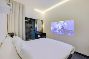 um quarto com uma cama branca e uma televisão em SUPPER Hotel em Amesterdão