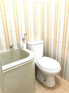 La salle de bains est pourvue de toilettes blanches et d'une baignoire. dans l'établissement Homestay Lavender C6 Palembang, à Palembang