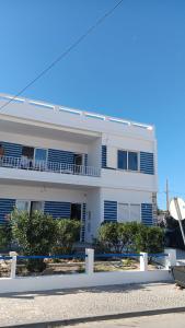 a white building with a balcony on the side of it at BLife Faro Beach Hostel in Faro