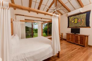 1 dormitorio con 1 cama blanca y TV en Two Bedroom Villa - Tamarindo, en Islita