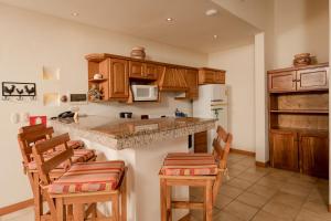 una cocina con armarios de madera y taburetes de bar en Two Bedroom Villa - Tamarindo, en Islita