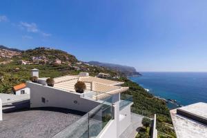a white house with a view of the ocean at Villa Harmonia by Place OverSea With Indoor Pool in Ponta do Sol
