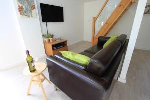 um sofá de couro preto numa sala de estar com uma garrafa de vinho em Orchard Nook - Sleeps 4, 2 Bedrooms (one ensuite) em Kendal