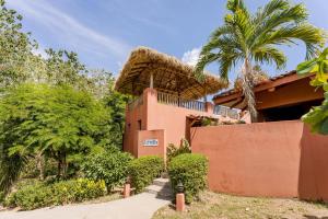 une maison avec un toit de chaume et un palmier dans l'établissement Three Bedroom Villa - Estrella, à Islita