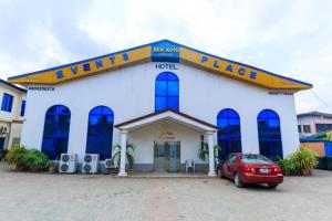 un grande edificio bianco con un'auto rossa parcheggiata di fronte di BEN AUTO Hotel a Lagos
