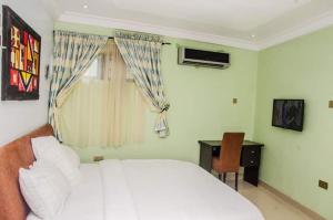 1 dormitorio con 1 cama blanca, ventana y escritorio en BEN AUTO Hotel en Lagos