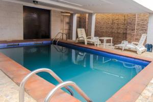 a large swimming pool with chairs and a television at BEN AUTO Hotel in Lagos