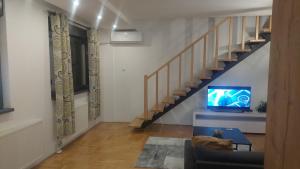 Una sala de estar con escalera y televisor. en Riverside apartment with private parking, en Niš