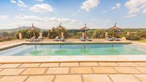 a swimming pool with chairs and umbrellas at Agroturismo son Calo in Petra