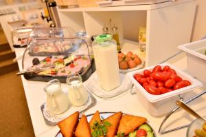 einen Tisch mit Teller mit Lebensmitteln und einer Flasche Milch in der Unterkunft Lucas Boutique Hotel in Eforie Nord
